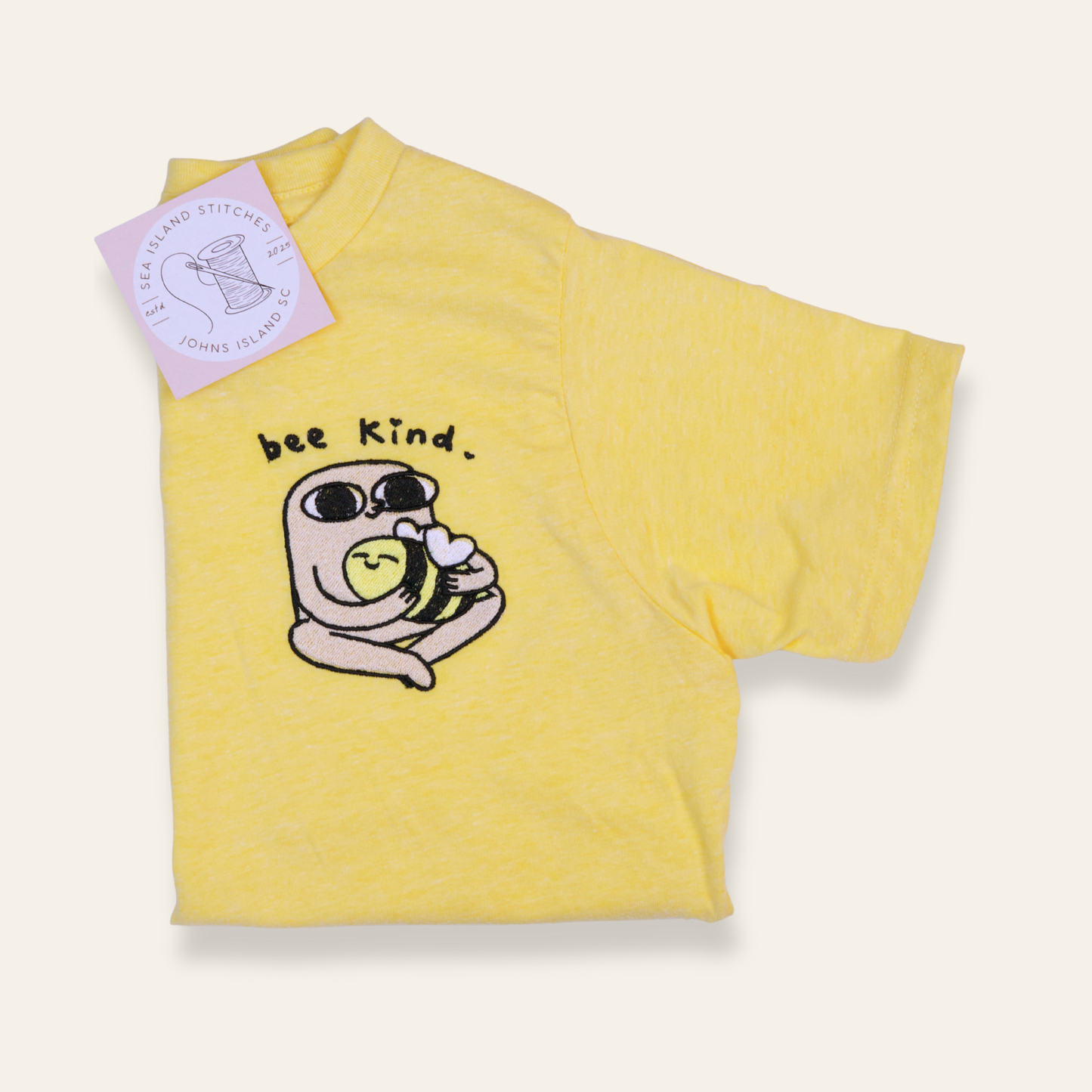 Yellow kids t-shirt featuring an embroidered bee and the phrase “bee kind.” Soft, cheerful, and perfect for everyday wear.