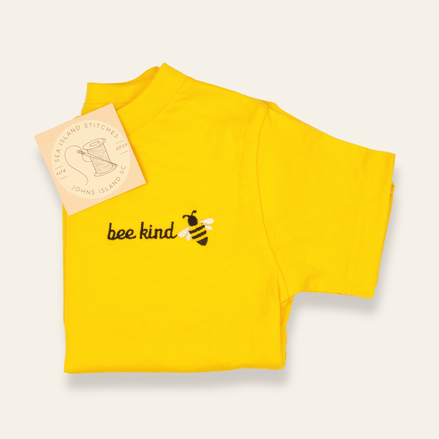 Yellow kids t-shirt featuring an embroidered bee and the phrase “bee kind.” Soft, cheerful, and perfect for everyday wear.