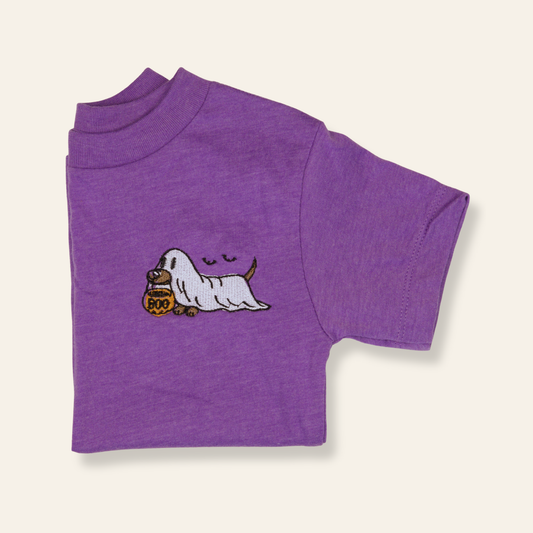 Purple kids t-shirt featuring an embroidered ghost dog with a candy bucket. Spooky-cute, playful, and perfect for fall.