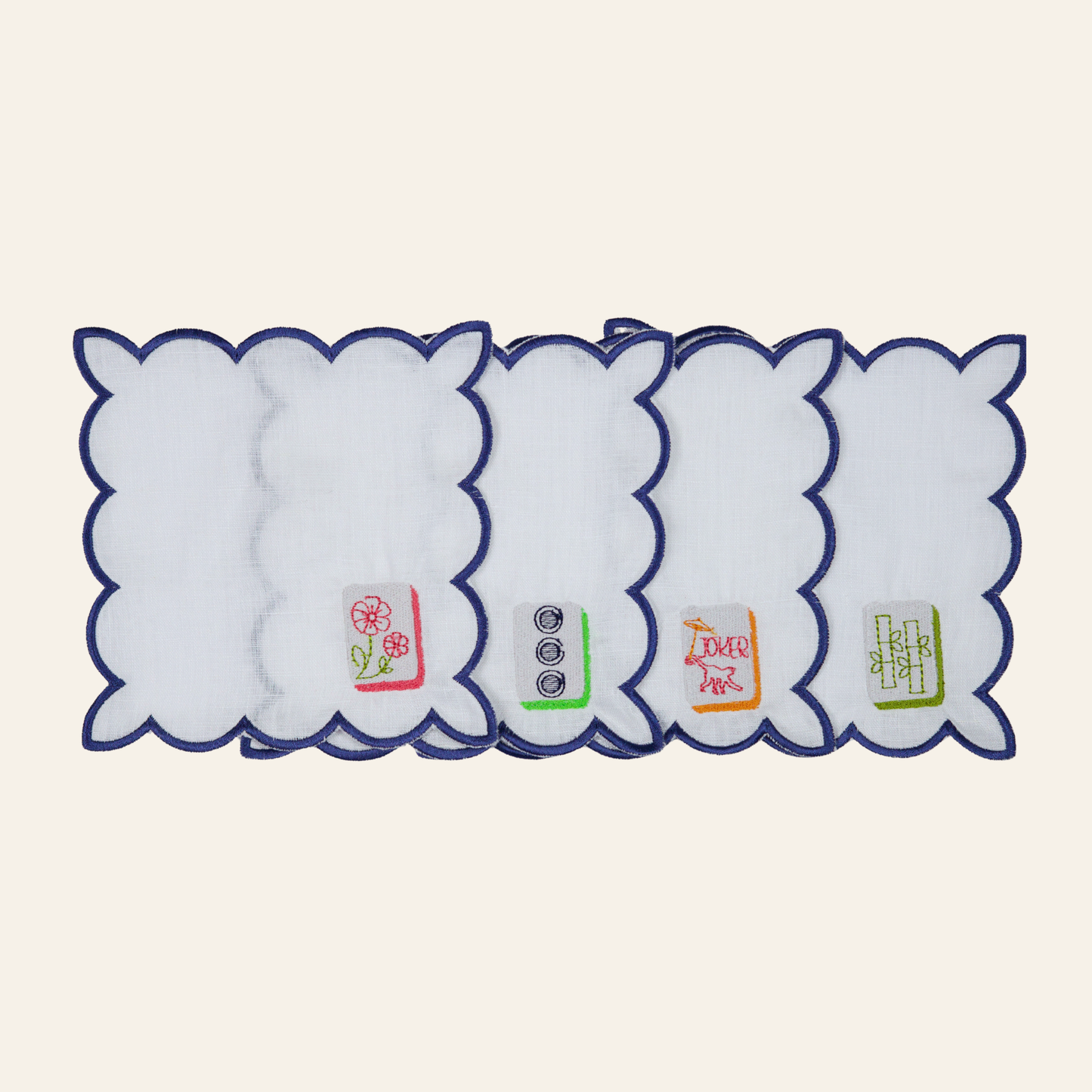 Set of four embroidered mahjong cocktail napkins with white fabric, navy scalloped edges, and colorful mahjong tile designs