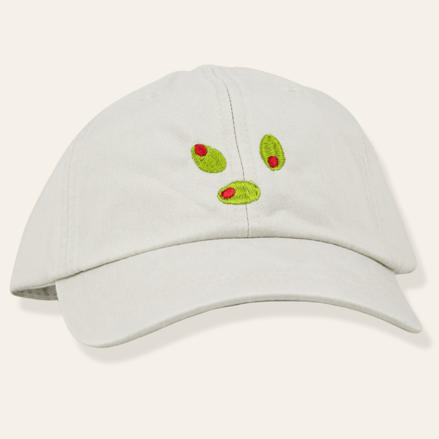 Beige embroidered cap featuring green olive martini garnish detail. Soft cotton twill with adjustable fit—perfect for cocktail lovers.