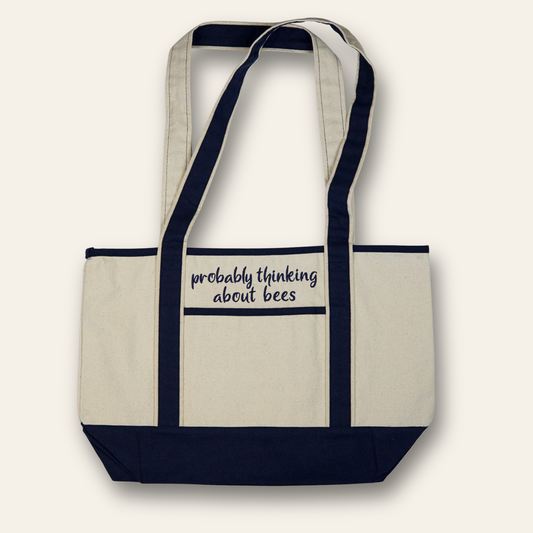 Embroidered canvas tote with navy trim and the phrase “probably thinking about bees.” A reusable, everyday bag perfect for errands or gifting.