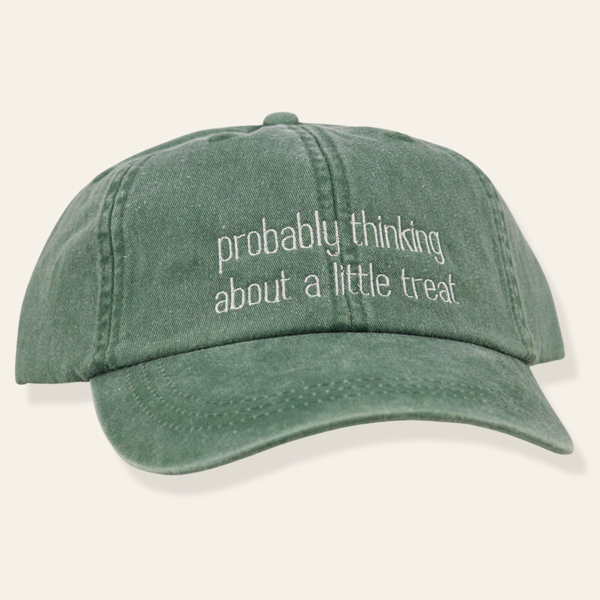 Washed green embroidered cap featuring “probably thinking about a little treat.” Soft cotton, adjustable fit, and a fun everyday accessory.