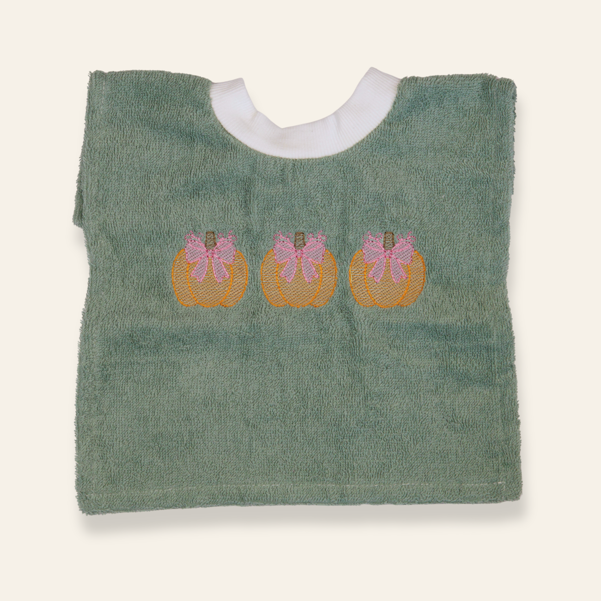 Sage green baby bib featuring embroidered pumpkins with pink bows. Soft, absorbent, and perfect for fall babies or seasonal gifting.