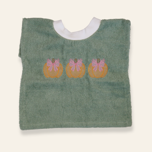 Sage green baby bib featuring embroidered pumpkins with pink bows. Soft, absorbent, and perfect for fall babies or seasonal gifting.