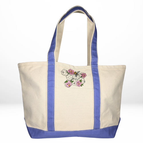 A beige canvas tote with violet trim, embroidered with soft pink flowers and a bee at the center atop a delicate honeycomb design, adding a gentle, feminine touch.