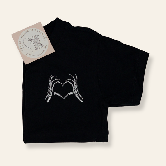Black kids t-shirt with embroidered skeleton hands forming a heart. Subtle, playful, and perfect for fall or everyday wear.