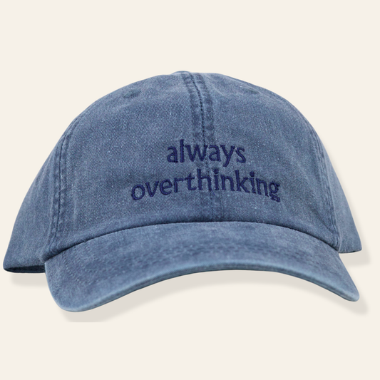Washed blue embroidered cap featuring “always overthinking.” Soft cotton, adjustable fit, and perfect for everyday wear. A relatable favorite.
